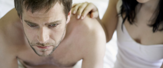 Young couple sitting at edge of bed, man worried, high angle view