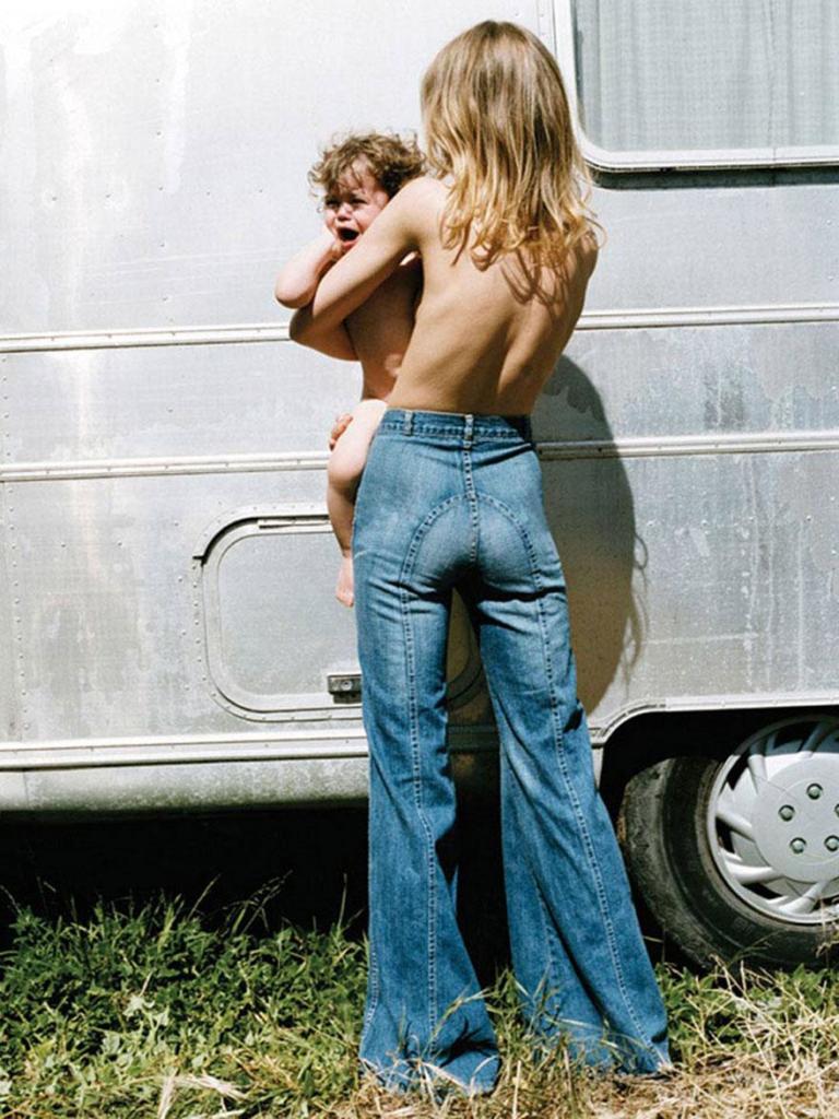 hippie-couple-standing-barefoot-on-a-road-holding-a-bundle-wine-bottle-at-woodstock-47__880