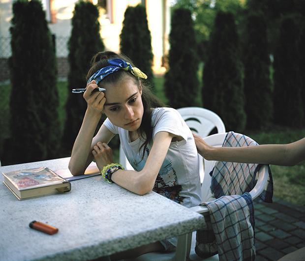 Ania sits outside and writes in her journal. She misses everyone back home.